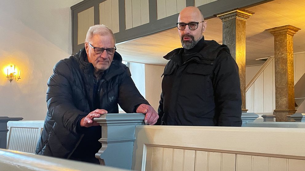 Två män inspekterar kyrkbänkarna i Tjärstad kyrka.