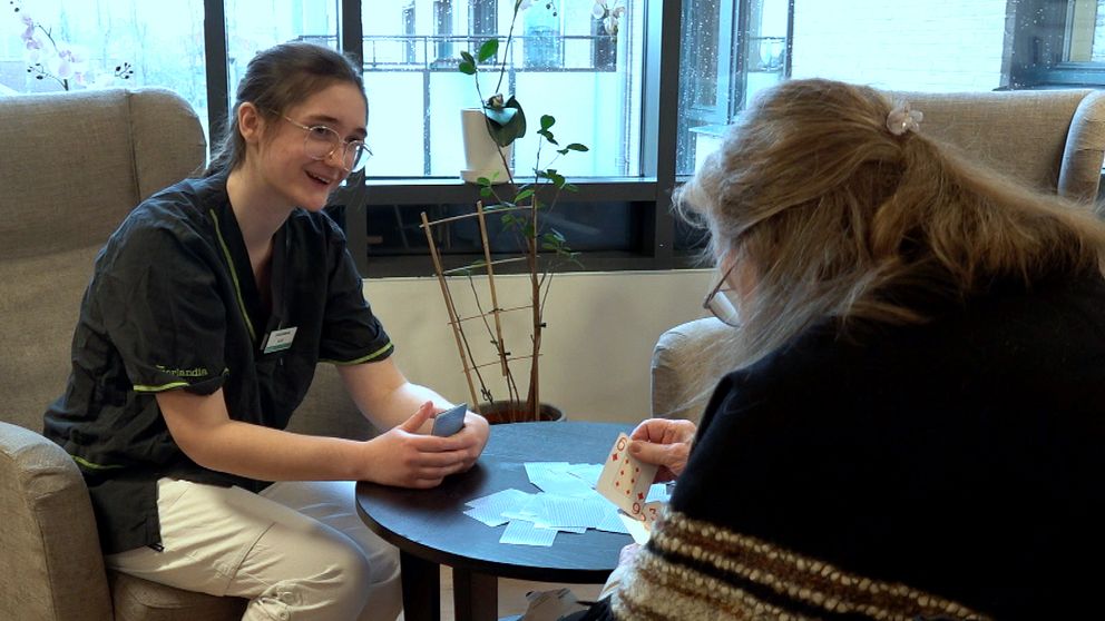 Jasmine Svensson spelar kort med en av de boende på det äldreboende i Fyllinge där hon har praktik.