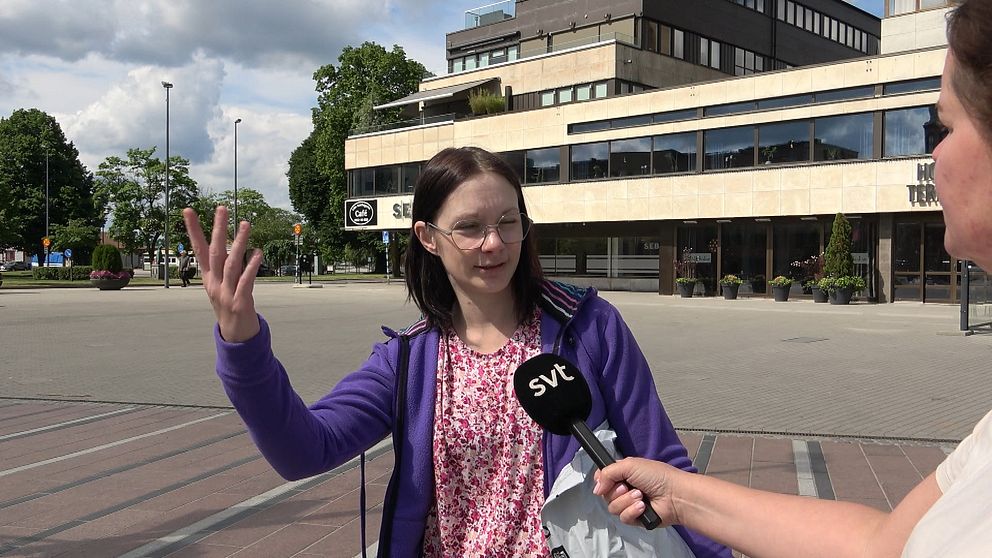 Kvinna viftar med armen på torget i Ljungby