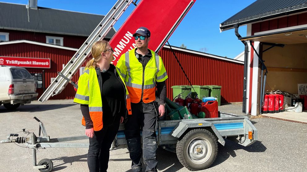 Carolina och hennes sambo Per-Arne står framför en röd släpvagn full med räddningsutrustning. De har reflexvästar på sig och står utanför affären i Överturingen.