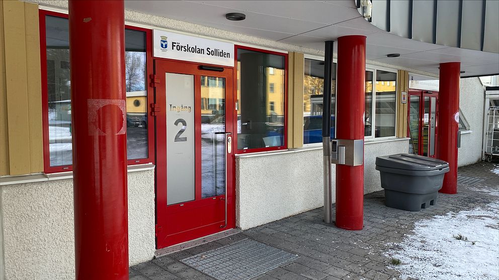 Entrén till Förskolan Solliden i Östersund. Dörren är röd och det är röda pelare. Det är lite snö på marken.