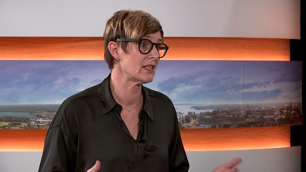 Person i en TV-studio med färgglad bakgrund.