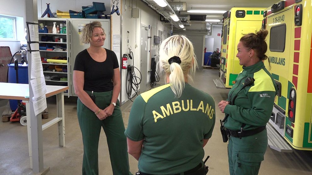 Tre kvinnor som pratar med varandra i ett ambulansgarage
