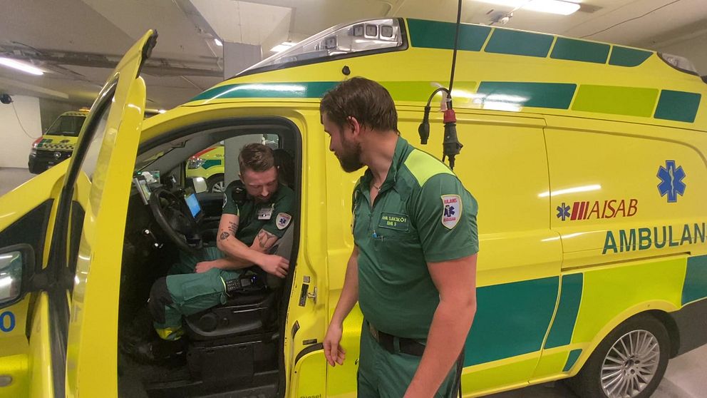 Två män iklädda gröna kläder vid en ambulans