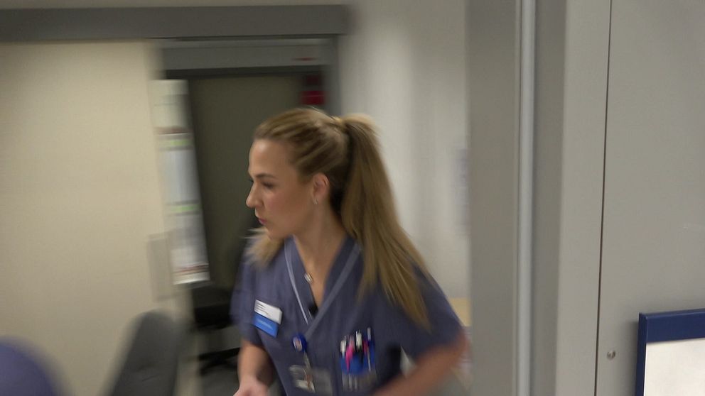 Sjuksköterskan springer ut från sitt arbetsrum mot en patient