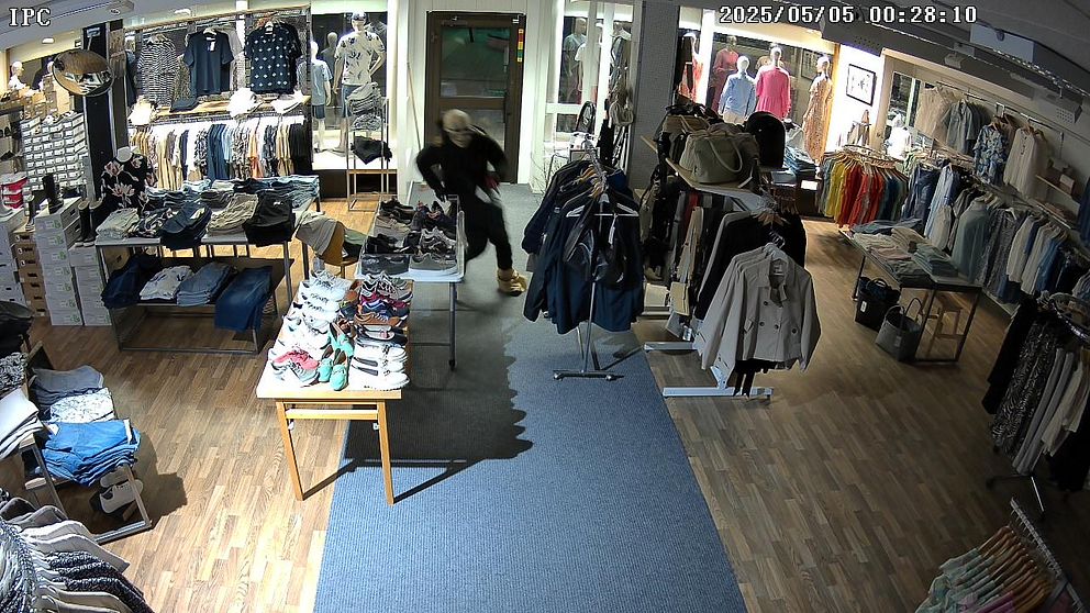 Bild från övervakningskamera som visar tjuv med dödskallemask inne i en butik.
