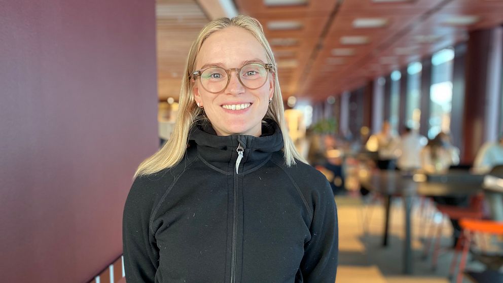 Ung kvinna med glasögon och blont hår står inne på Linköpings universitet.