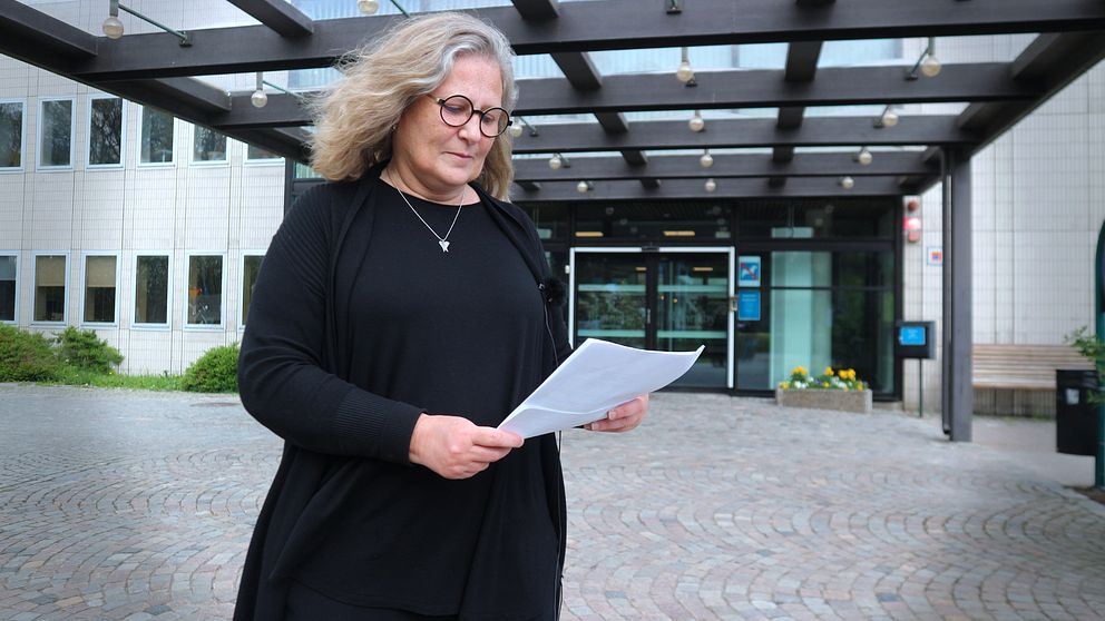 kvinna med papper i handen utanför Ronneby Stadshus