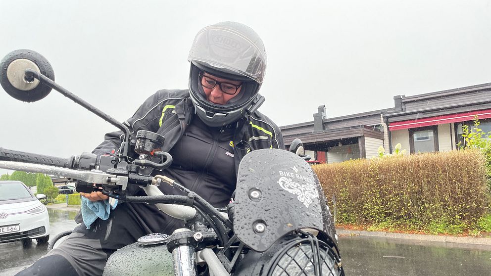 En kvinna på motorcykel med hjälm.