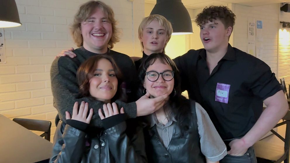 Occrasy, ett dalaband som ler in i kameran. två tjejer och tre killar i mörka kläder. rockband.
