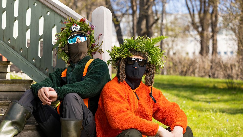 Hooja och DJ Mårdhund sitter utomhus på en trappa med sommarkransar.