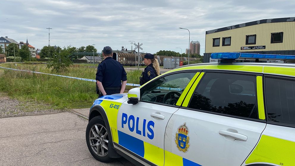 Två poliser övervakar avspärrningarna vid järnvägsstationen i Landskrona där en död kvinna hittats. Polisen misstänker mord.
