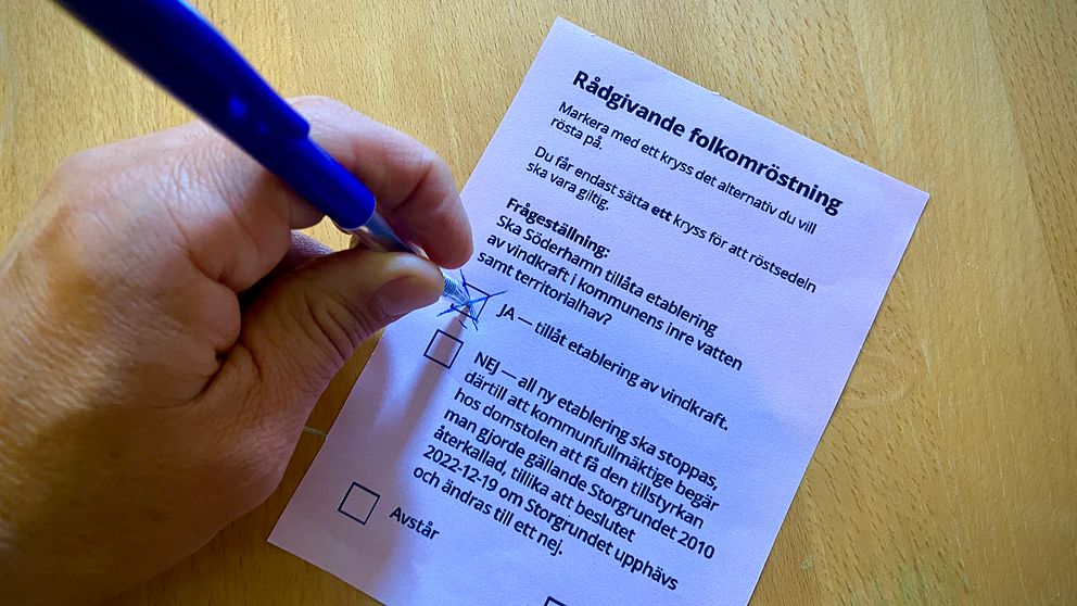 Röstsedel och en hand som kryssar Ja