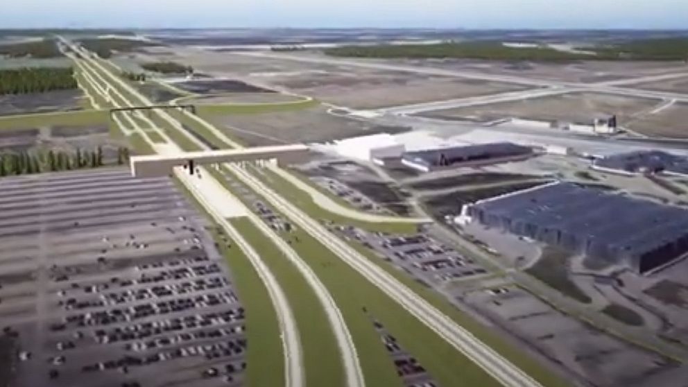 Flygbild över en stor industrikomplex med parkeringsplats och omgivande vägar.