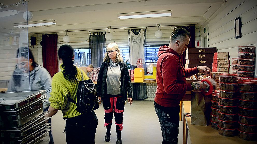 Folk som packar kassar med pepparkakor och bröd i en lokal