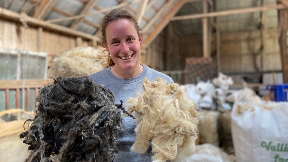 Charlotte Jansson håller glatt upp två olika sorters ull, en grå och en vit.
