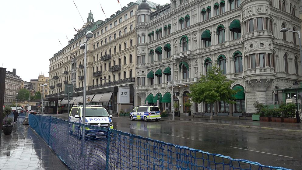 Två polisbilar står parkerade på en avspärrad gata framför ett hotell i centrala Stockholm.