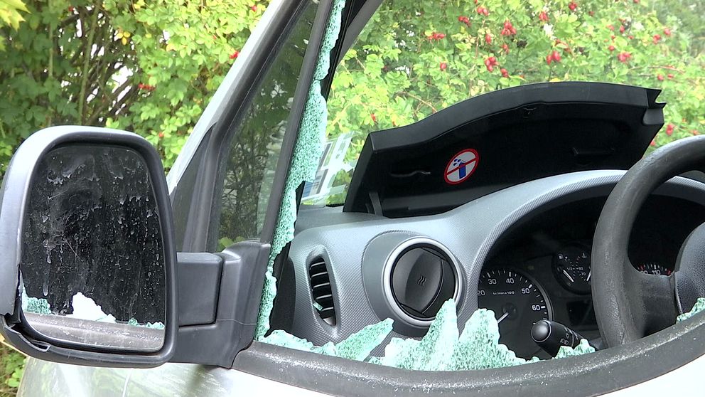 Ett bilfönster är krossat, och det finns glassplitter utspritt över dörren och instrumentbrädan.