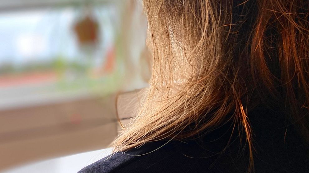 Kvinna i mört hår sitter med ryggen vänd