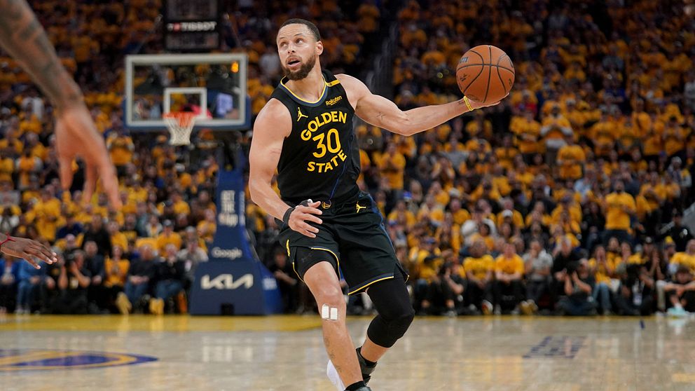 Basketspelaren Stephen Curry driver bollen under match inför publik på fullsatt arena.