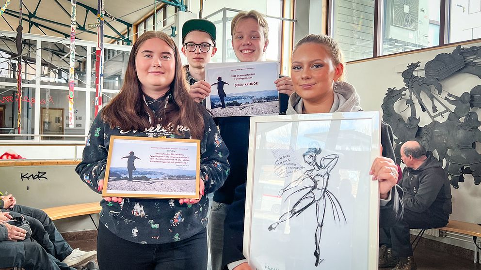 Fyra personer visar upp teckningar och tavlor med dansmotiv inomhus.