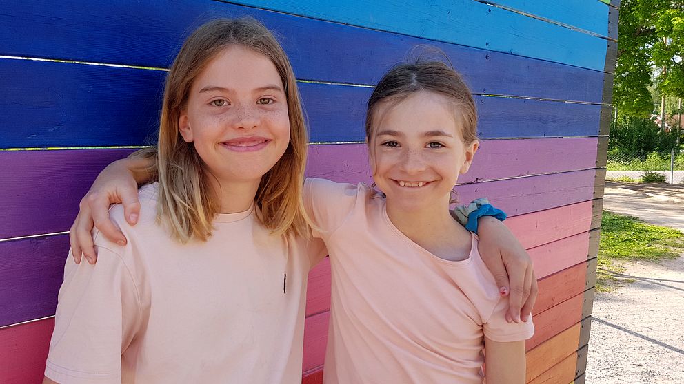 två flickor framför ett målat staket