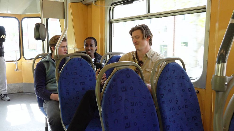 Tre personer sitter på säten i en spårvagn.