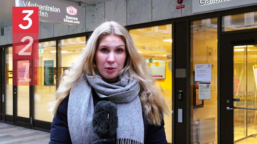 Reporter Frida Gunnvald står framför Vårdcentralen Gallerian med en mikrofon i handen.