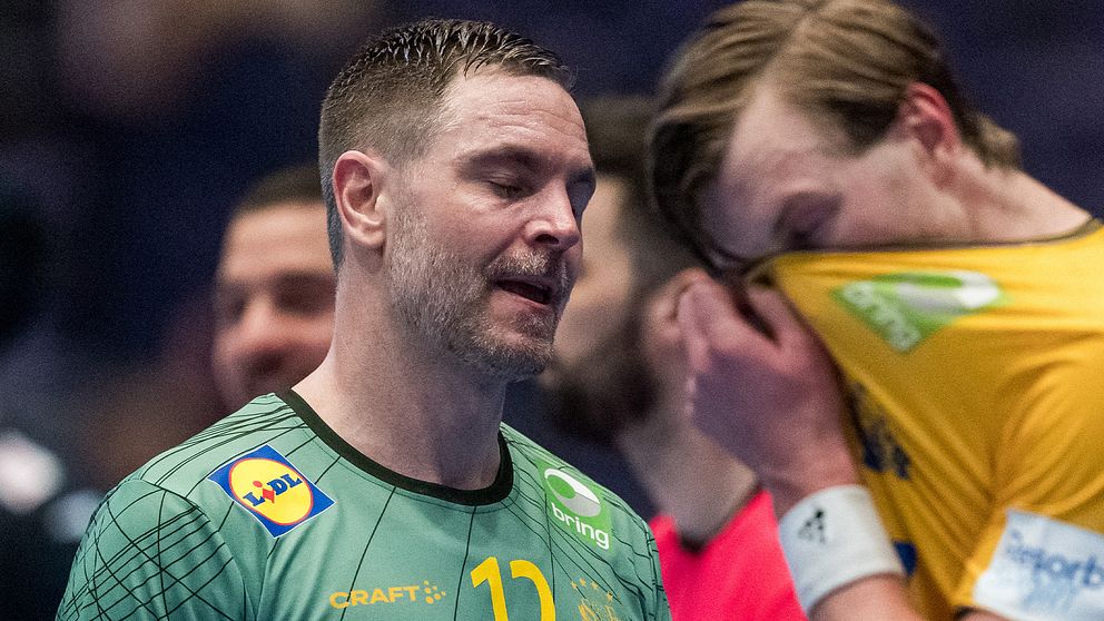 Två handbollsspelare i diskussion på planen, en spelare iförd en grön tröja med nummer 11 och en annan i en gul tröja. Båda ser koncentrerade ut, vilket tyder på en viktig taktisk genomgång under matchen.