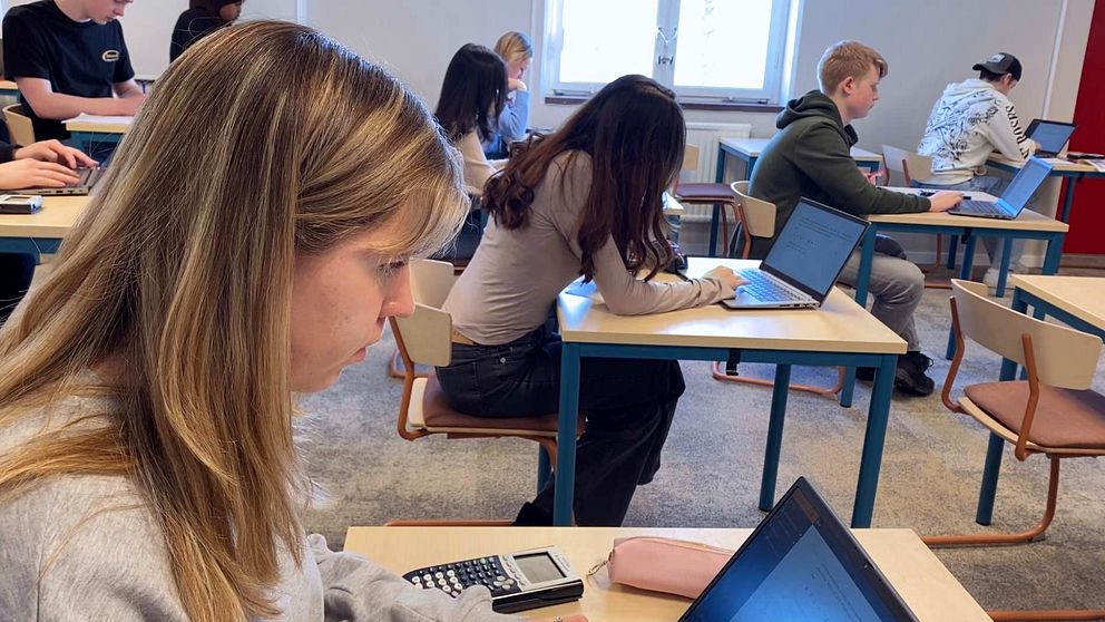 Ett klassrum där eleverna sitter med varsin laptop. Närmast kameran syns två tjejer, längre bort sitter några killar,.