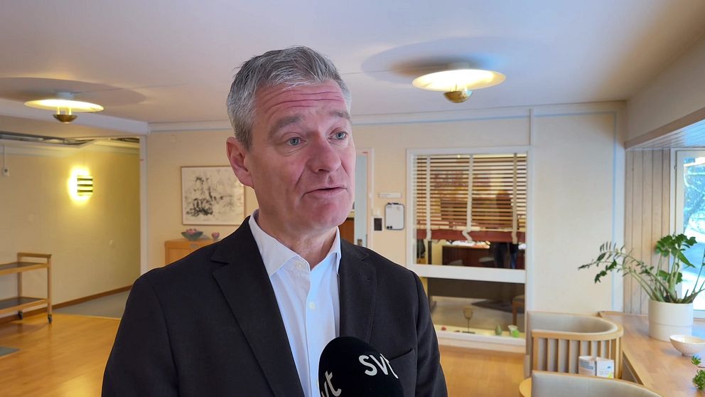 Rickard Simonsson, regiondirektör i Örebro län, syns stående i kontorsmiljö i halvkroppsbild med en mikrofon framför sig.