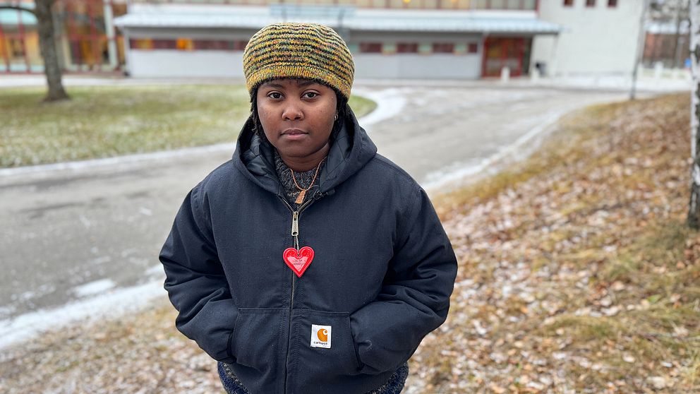 June står framför Falu tingsrätt, klädd i en svart jacka med en röd hjärtformad hängsmycke.