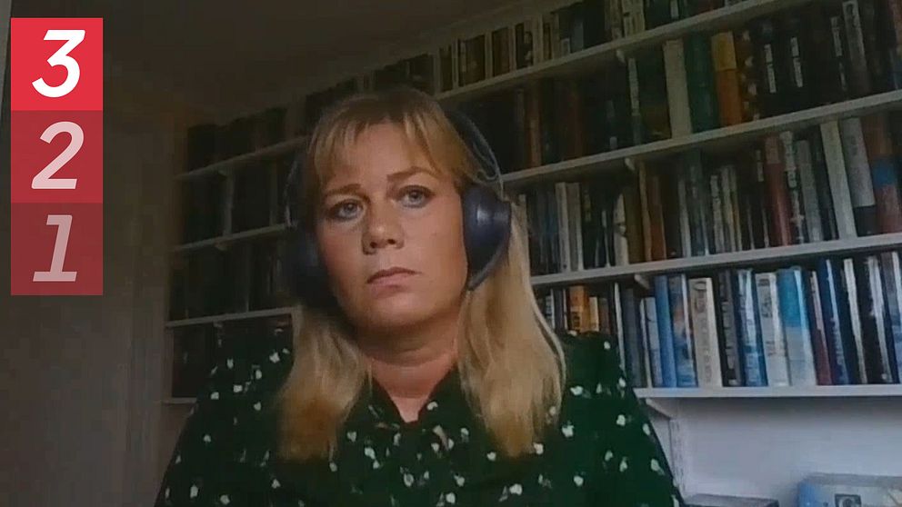 en kvinna med hörlurar framför en hylla med massa böcker