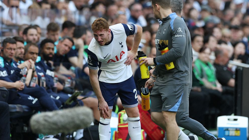 En Tottenhamspelare håller sig för höften och får hjälp vid sidlinjen under en match.