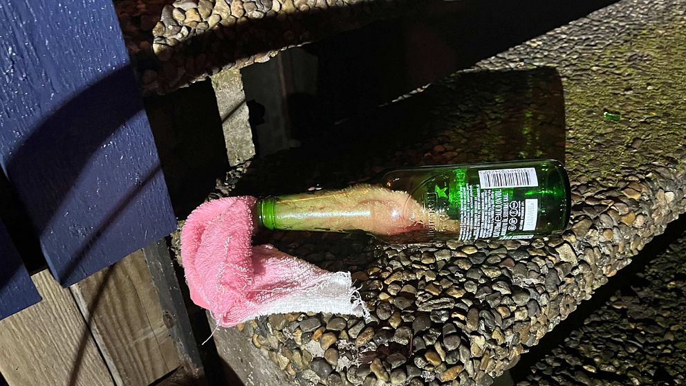 Bild på en av flaskorna som hittades vid adressen. En grön glasflaska med en rosa trasa som sticker ut ur flaskhalsen.