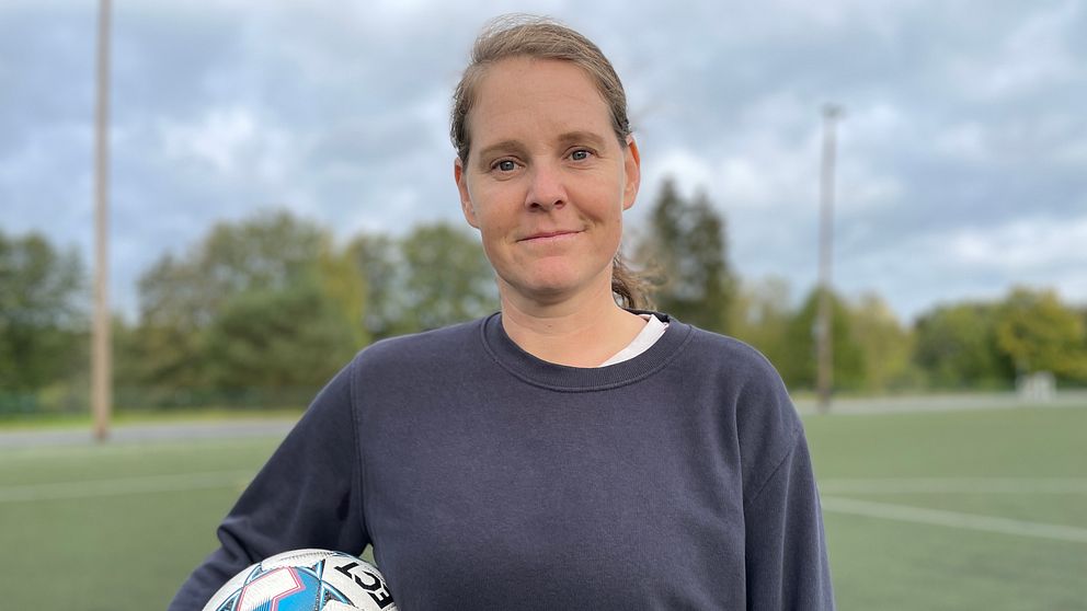 Biträdande universitetslektor Emma Lindkvist på fotbollsplan hållandes boll