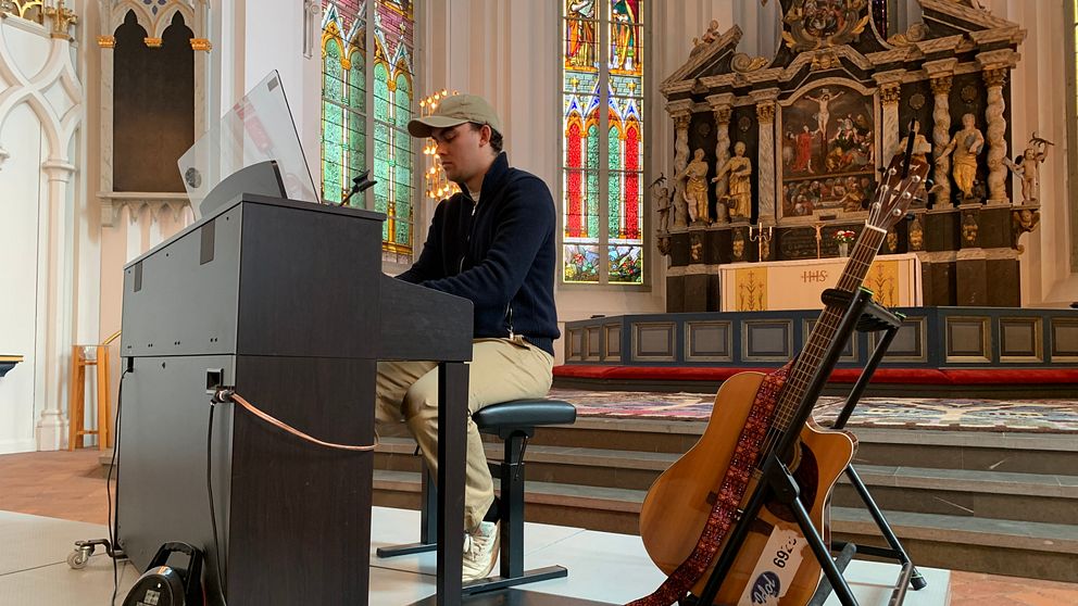 Före detta idoldeltagaren Luka Nemorin sitter vid ett piano och spelar i en kyrka i Kristinehamn