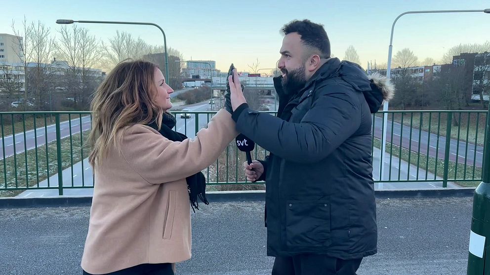 Fanny Berg och Hamza Ftouni gör high five på en bro över trafikerad gata.