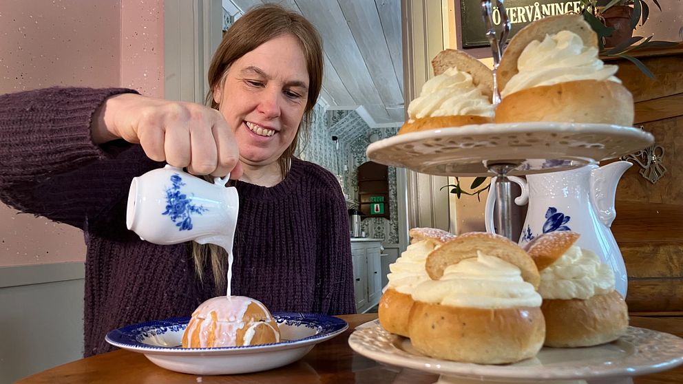 kvinna häller hetmjölk över en semla