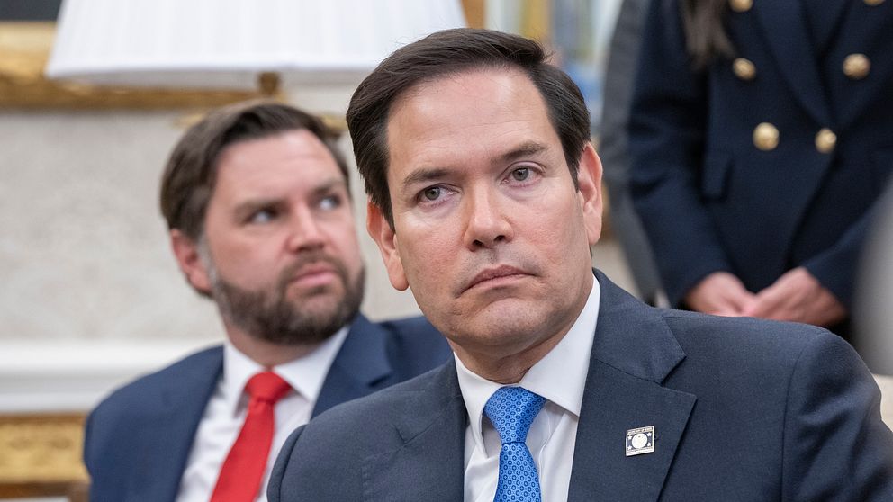 JD Vance och Mark Rubio i kostym sitter bredvid varandra vid ett möte i officiell miljö.