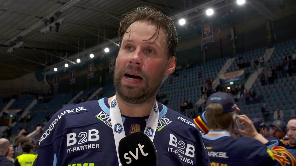 Ishockeyspelare intervjuas av SVT efter match, med medalj runt halsen i fullsatt arena.