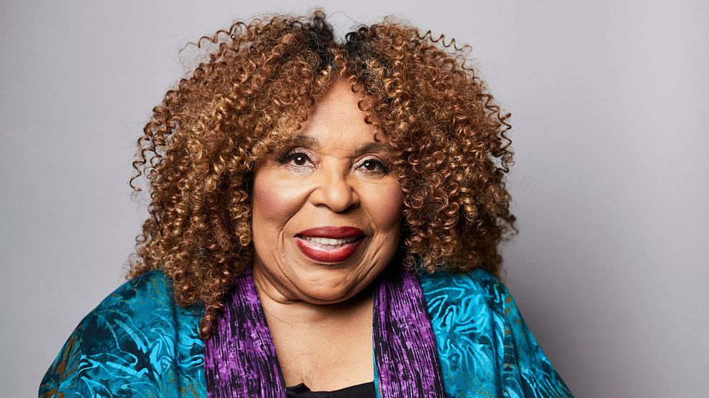 Roberta Flack i färgglad klädsel framför en grå bakgrund.