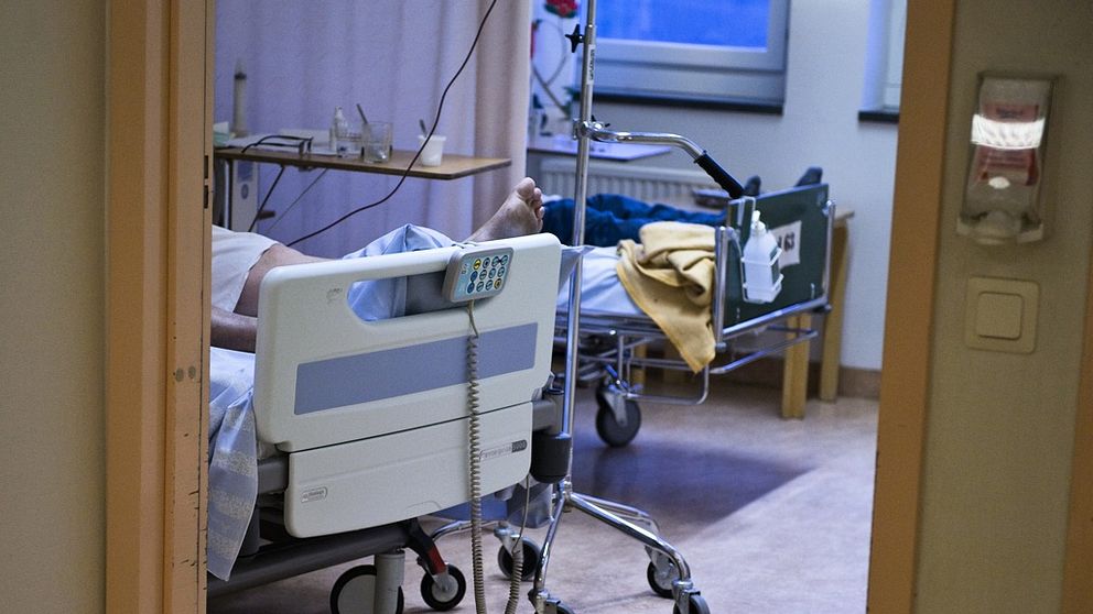 Två patienter som ligger i varsin sjukhussäng i ett rum.