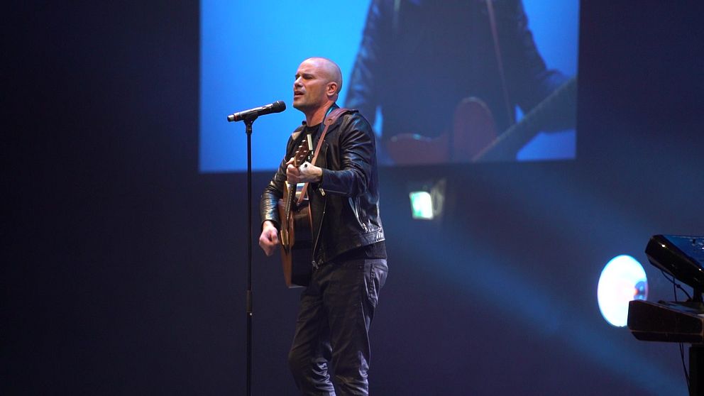 Man med gitarr sjunger på scen under ett framträdande på idrottsgalan i Örebro.