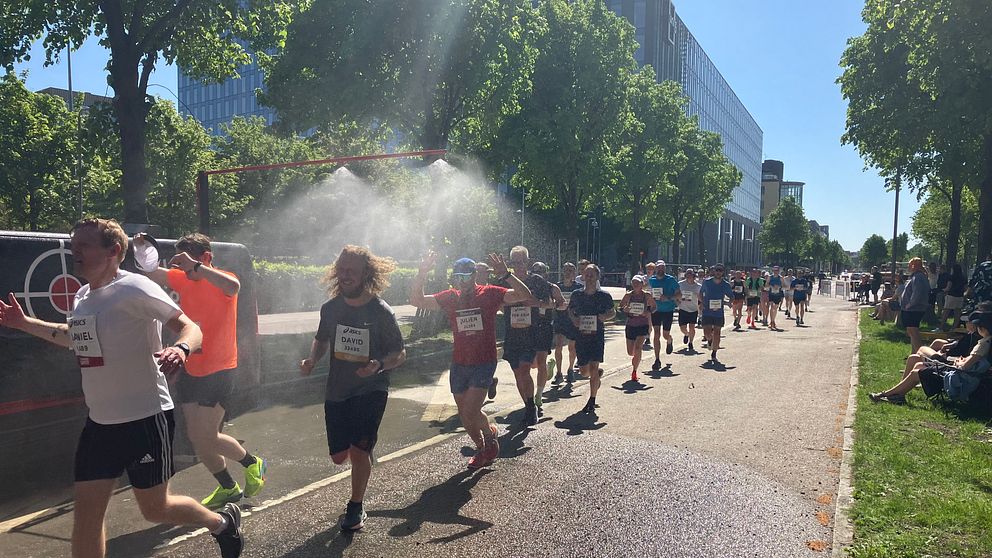 Löparna på Göteborgsvarvet springer genom en sprinkler.