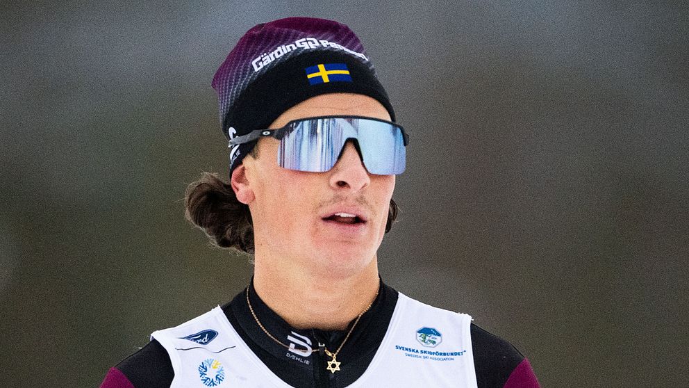 Skidåkare med svensk flagga på pannbandet, vintermiljö.