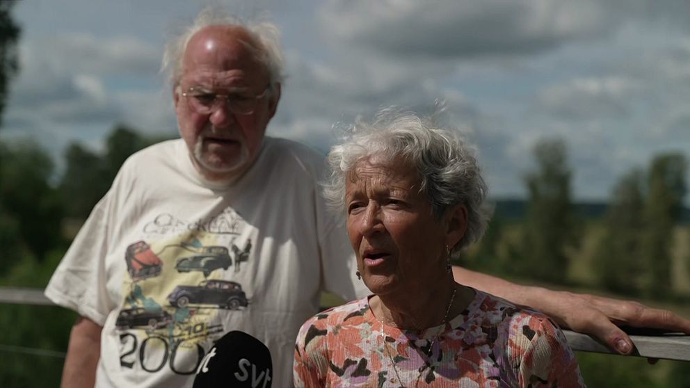 Två äldre personer står utomhus med en SVT-mikrofon framför sig.