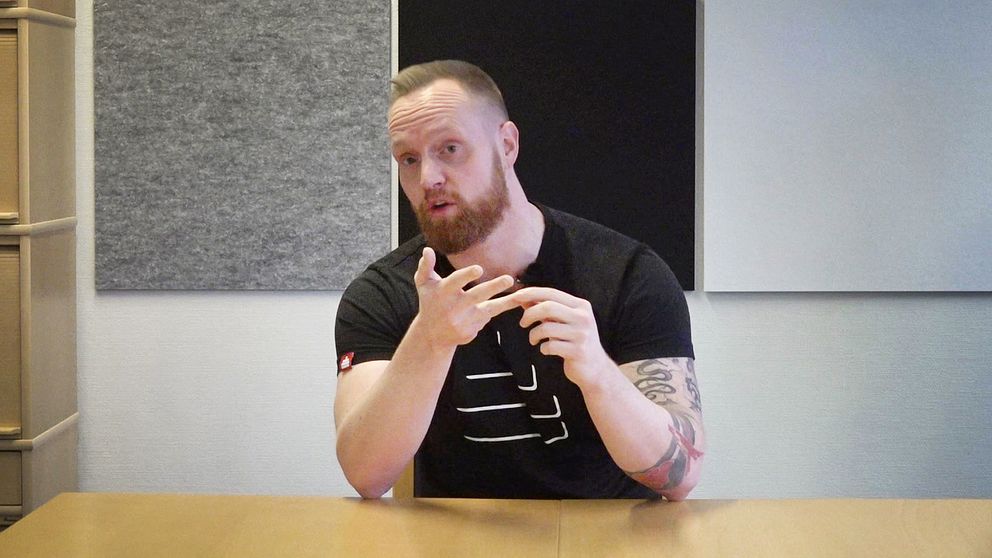 Tage Norén från Frivåden i Eskilstuna, kortklippt man i svart t-shirt, sitter ned vid skrivbord och pratar om hur de jobbar med kriminella ungdomar