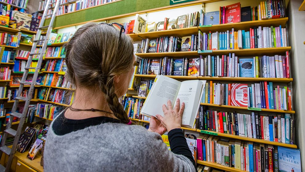 Kvinna i bokhandel läser bok.