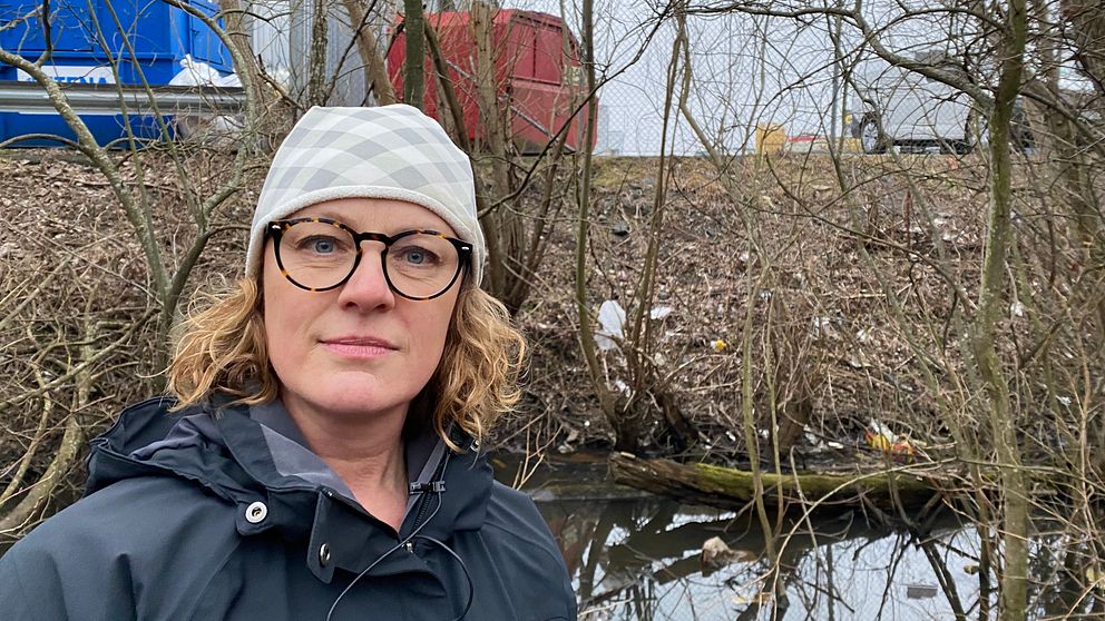 Katarina Ås står framför en skräpfylld bakgrund vid Rocksjöns naturreservat.